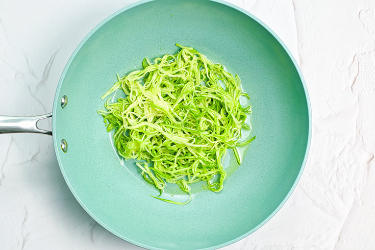 Zucchini pasta in a skillet with oil.