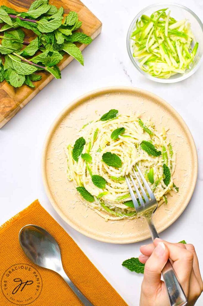 A fork reaches for a fork-full of zucchini pasta.