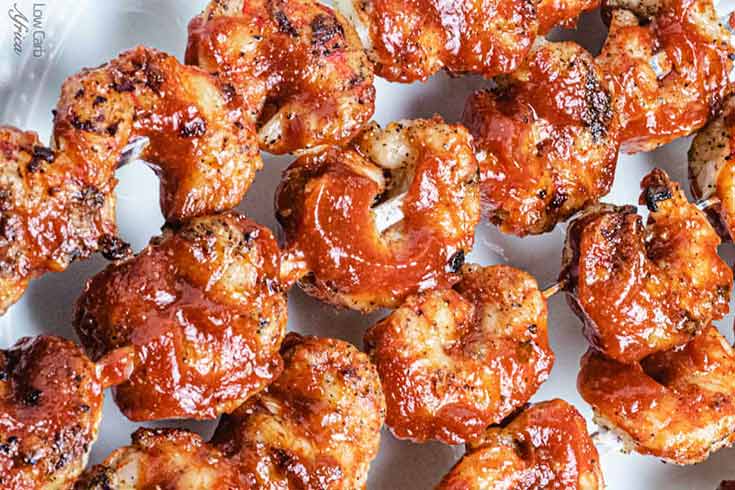 An overhead view of shrimp skewers on a white platter.