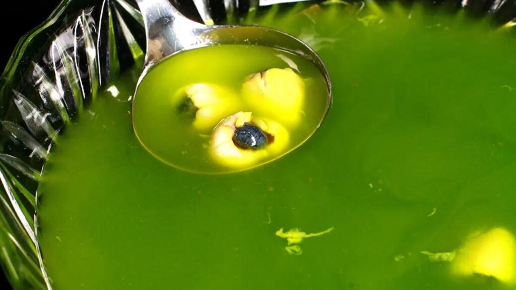 Bowl of green punch with eyeballs in a ladle.