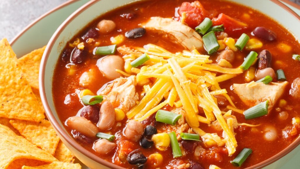 A bowl filled with chicken tortilla soup with a side of corn chips.