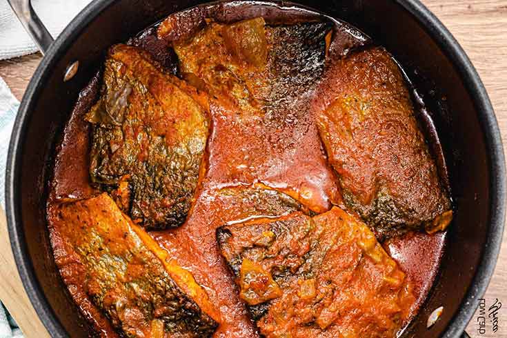 A black pot filled halfway with salmon stew.
