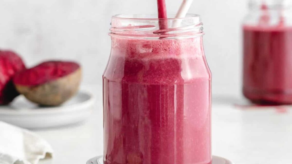 A closeup of a glass jar being filled with beetroot smoothie.