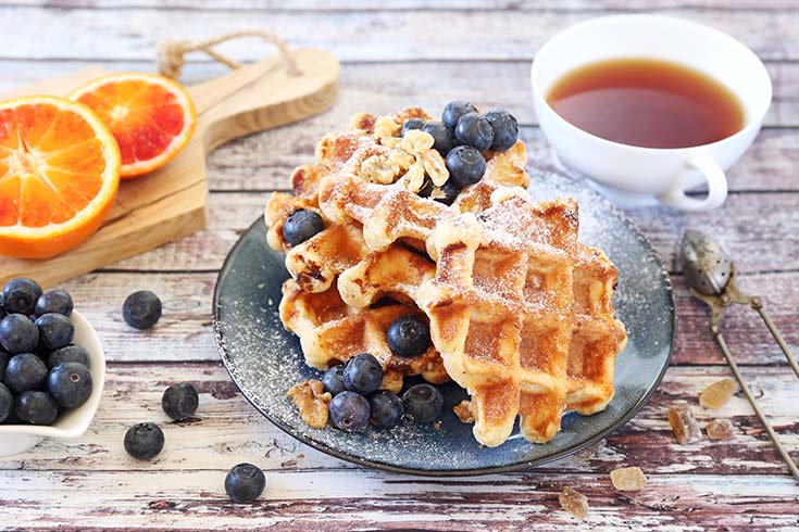 A plate of Belgian waffles with fresh blueberries on top.