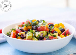 Front view of a white bowl filled with black bean salad, sitting on a table.