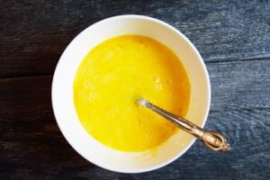 Eggs whisked in a white bowl with a fork.