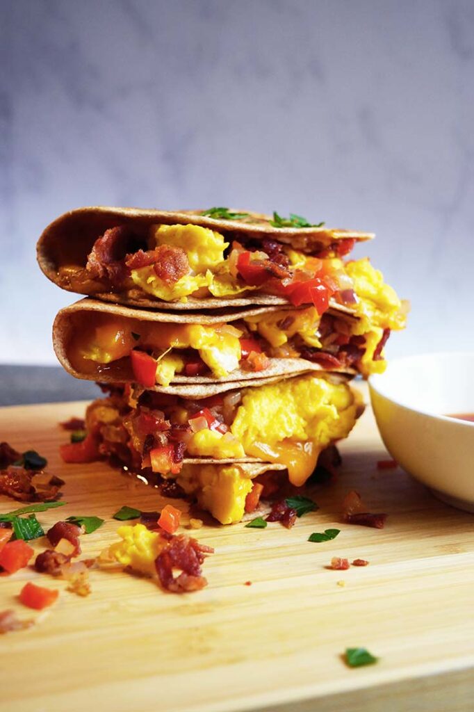 A front view of a Breakfast Quesadilla, cut, stacked, and sitting on a cutting board.