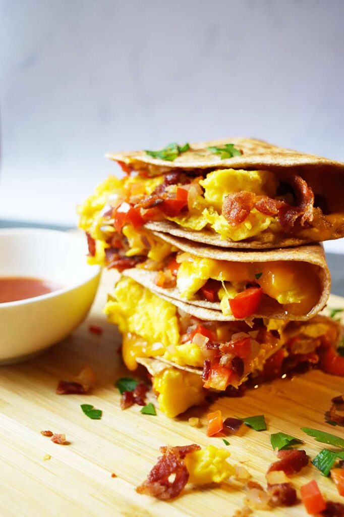 A side view of a cut and stacked Breakfast Quesadilla on a cutting board.