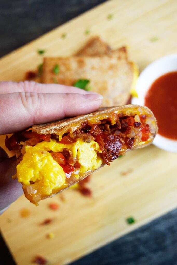 A hand picks up a piece of a Breakfast Quesadilla.