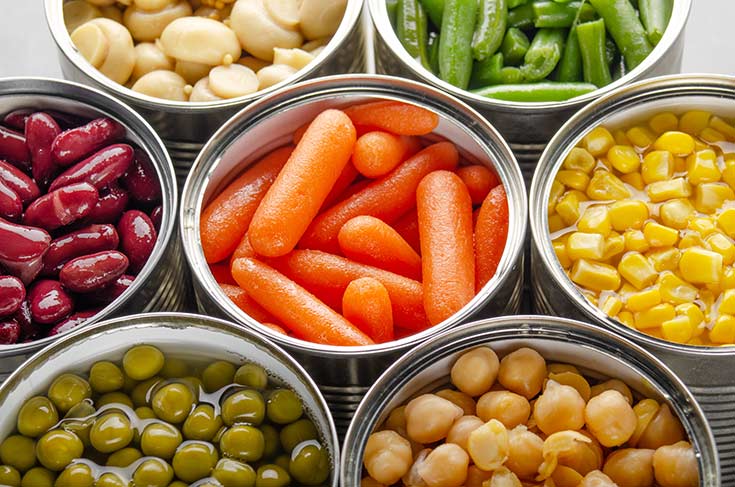 A group of opened cans with different vegetables in them.