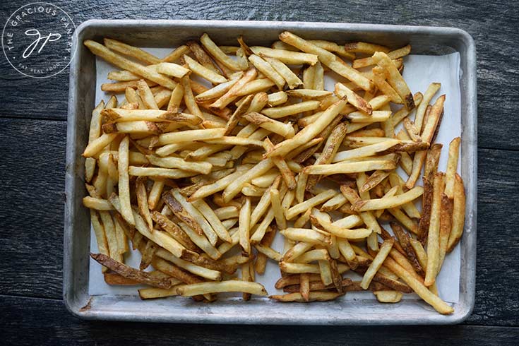 A sheet pan loaded with cooked french fries.