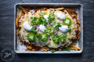 Chili Cheese Fries with toppings of sour cream, jalapeno pepper slices and fresh cilantro.