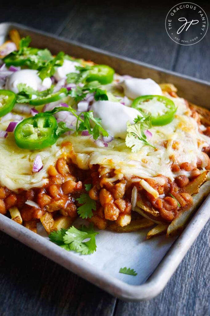 A sheet pan full of Chili Cheese Fries with a corner portion removed.