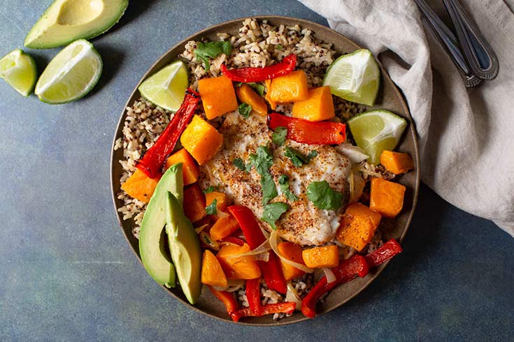 A bowl filled with a bed of rice with roasted butternut squash and a fillet of cod on top.