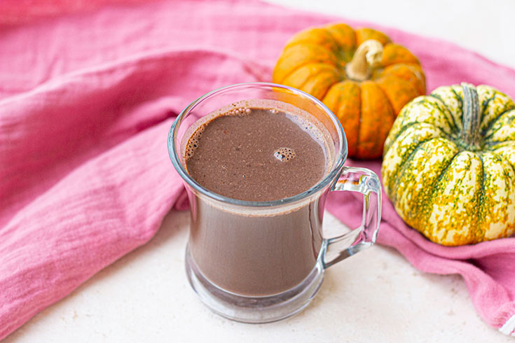 Pumpkin hot chocolate poured into a glass mug.