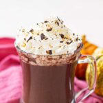 A front view of a glass mug filled with pumpkin spice hot chocolate.