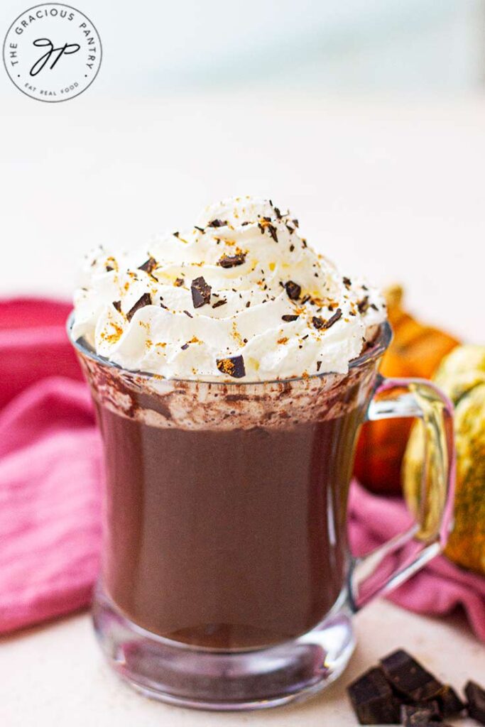 A front view of a glass mug filled with pumpkin spice hot chocolate.