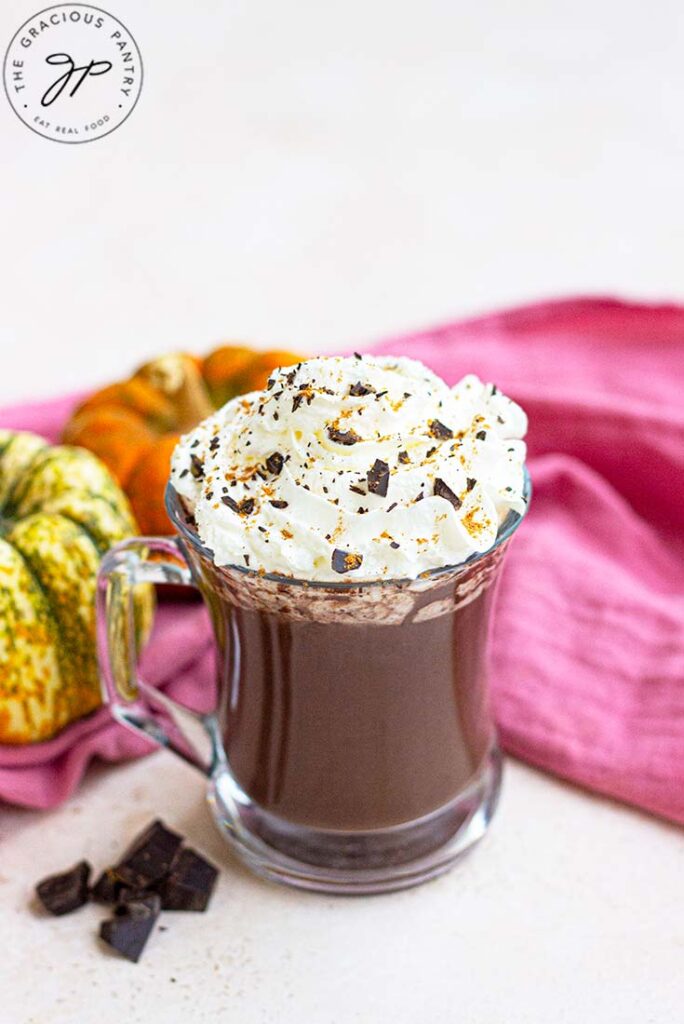 A side view of a glass mug filled with pumpkin spice hot chocolate.