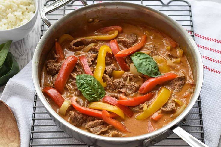 A skillet filled with beef curry and bell peppers strips.