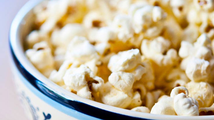 A decorative blue bowl filled with popcorn.