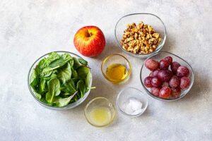 Grape Salad Recipe ingredients in individual bowls on a gray surface.