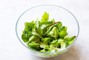 Spring greens in a clear, glass mixing bowl.