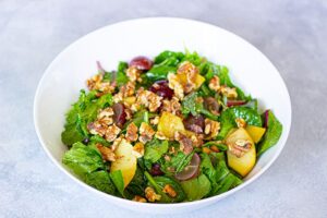 Nut and dressing added to this Grape Salad recipe in a white serving bowl.