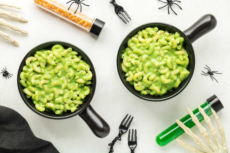 Two black bowls filled with green mac and cheese.