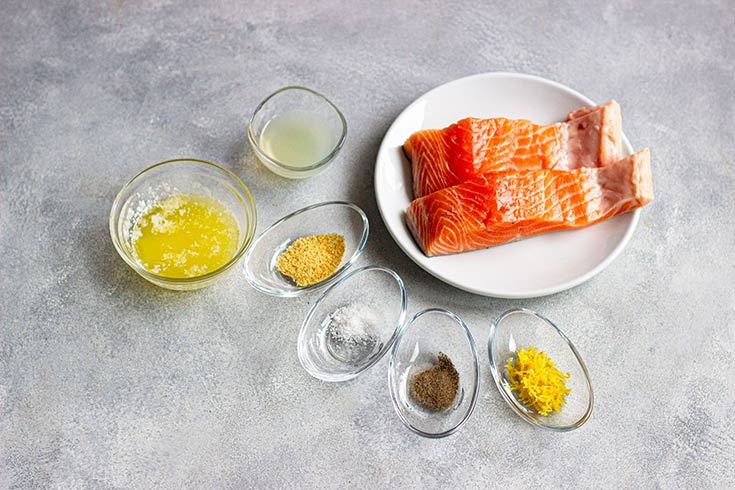 Ingredients for this Lemon Salmon Recipe in individual bowls on a gray surface.