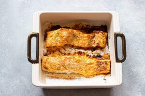 Two baked lemon salmon fillets in a baking dish.