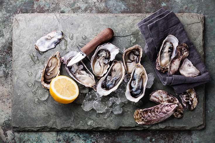 A slate board covered in opened oysters.