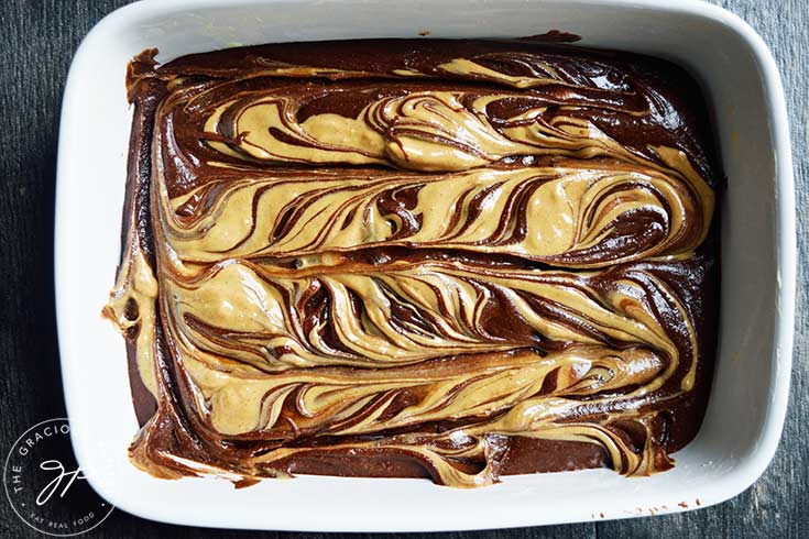 Peanut butter mix swirled through the brownie batter in a casserole dish.