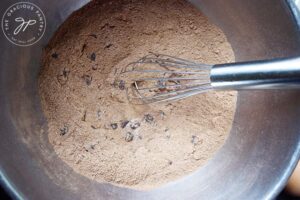 Chocolate chips mixed into a flour mix in a mixing bowl.