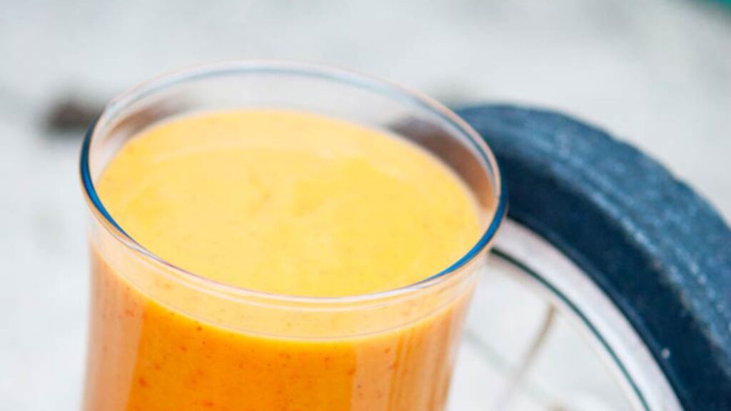 A Kid's Persimmon Smoothie in a glass next to a tricycle wheel.