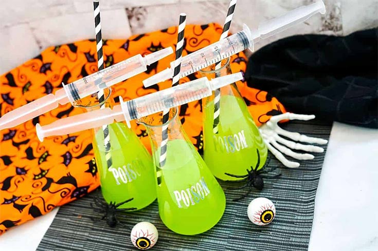 Flasks filled with poison halloween punch sit with empty syringes laying over the top.