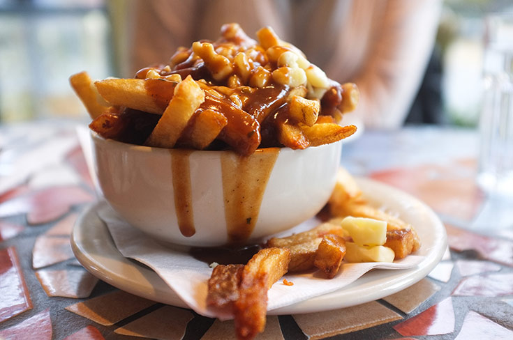 A white bowl filled with poutine fries.