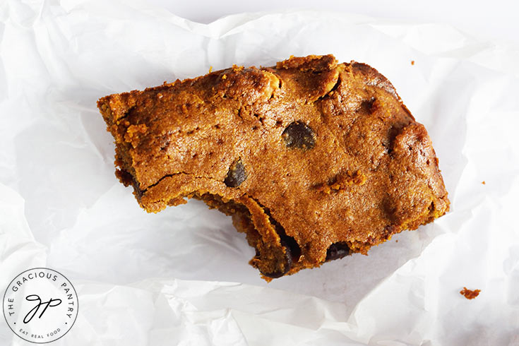 A single Pumpkin Blondie with a bite removed, on white parchment paper.