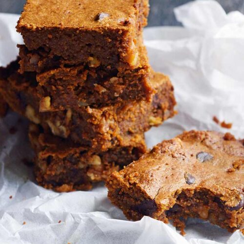 A stack of Pumpkin Blondies on parchment paper.