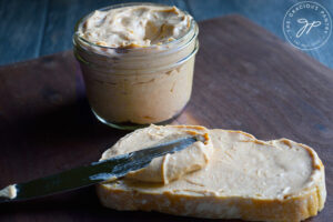 A knife spreads some pumpkin cream cheese over a slice of bread.