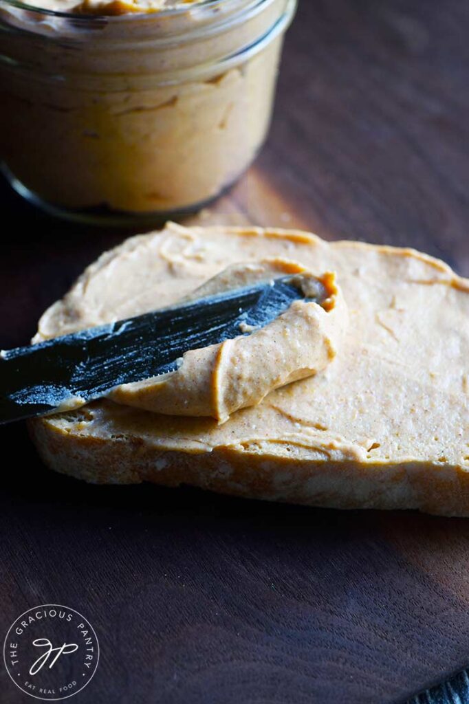 A knife spreading pumpkin cream cheese over a slice of bread.