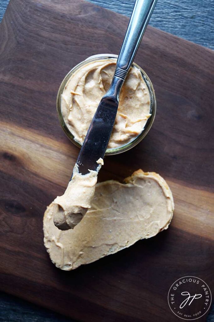 An overhead view of a knife laying across an open jar of pumpkin cream cheese.