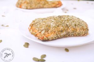 Two plates hold a fillet of Pumpkin Seed Crusted Salmon.