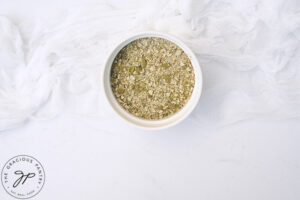 Ground pumpkin seeds in a white bowl on a white table.