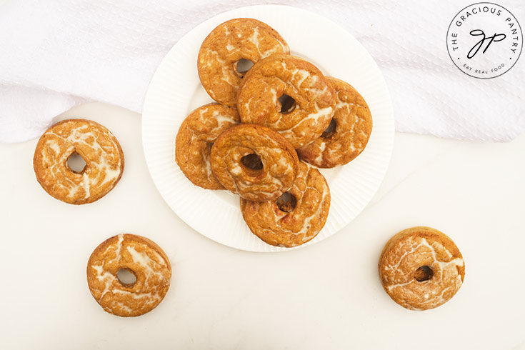 An overhead view of Pumpkin Donuts on a white plate and a white table.
