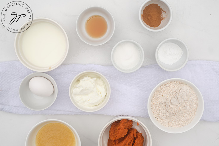 Ingredients for Pumpkin Donuts in individual bowl on a white table.