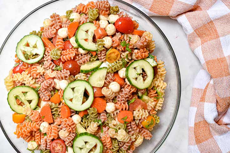 A plate of pasta with cucumber sliced to have pumpkin faces in them.