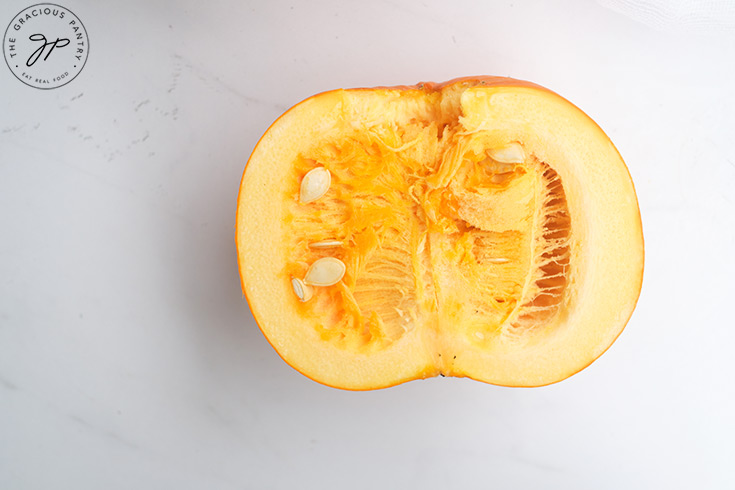 A single half pumpkin, cut side up, on a white surface.