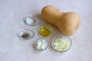 Recipe ingredients in individual bowls next to a whole butternut squash.