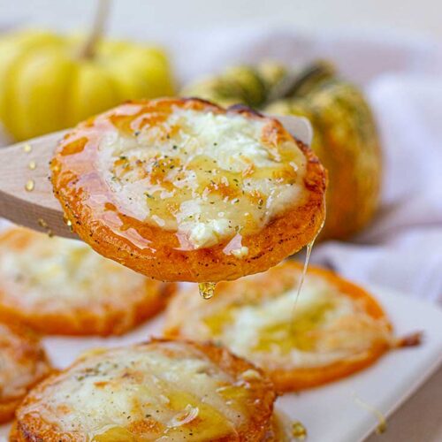 A front view of a wooden spoon lifting a slice of butternut squash off of a platter.