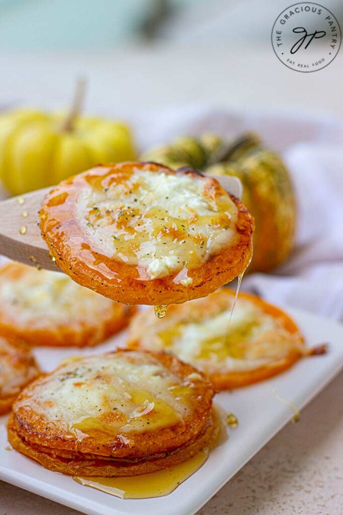 A front view of a wooden spoon lifting a slice of butternut squash off of a platter.